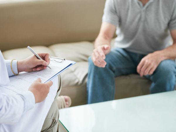 doctora-irreconocible-hablando-paciente-escribiendo-visita-domicilio